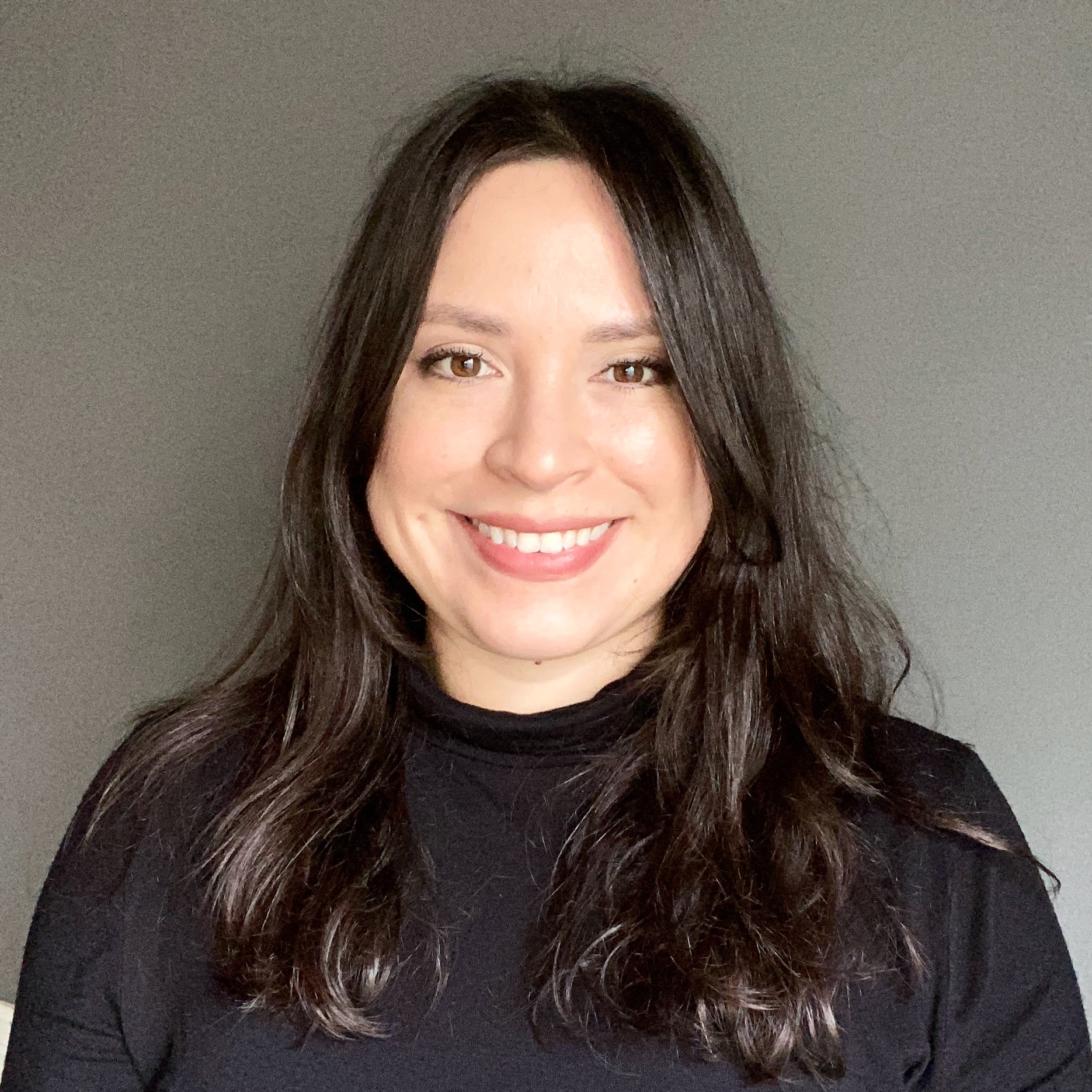 A woman with black hair and a black shirt smiles at the camera