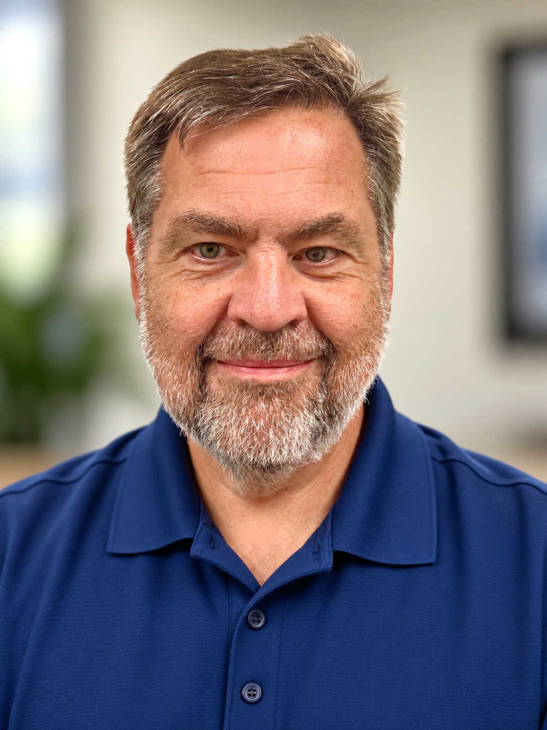 A man with a blue shirt smiles at the camera