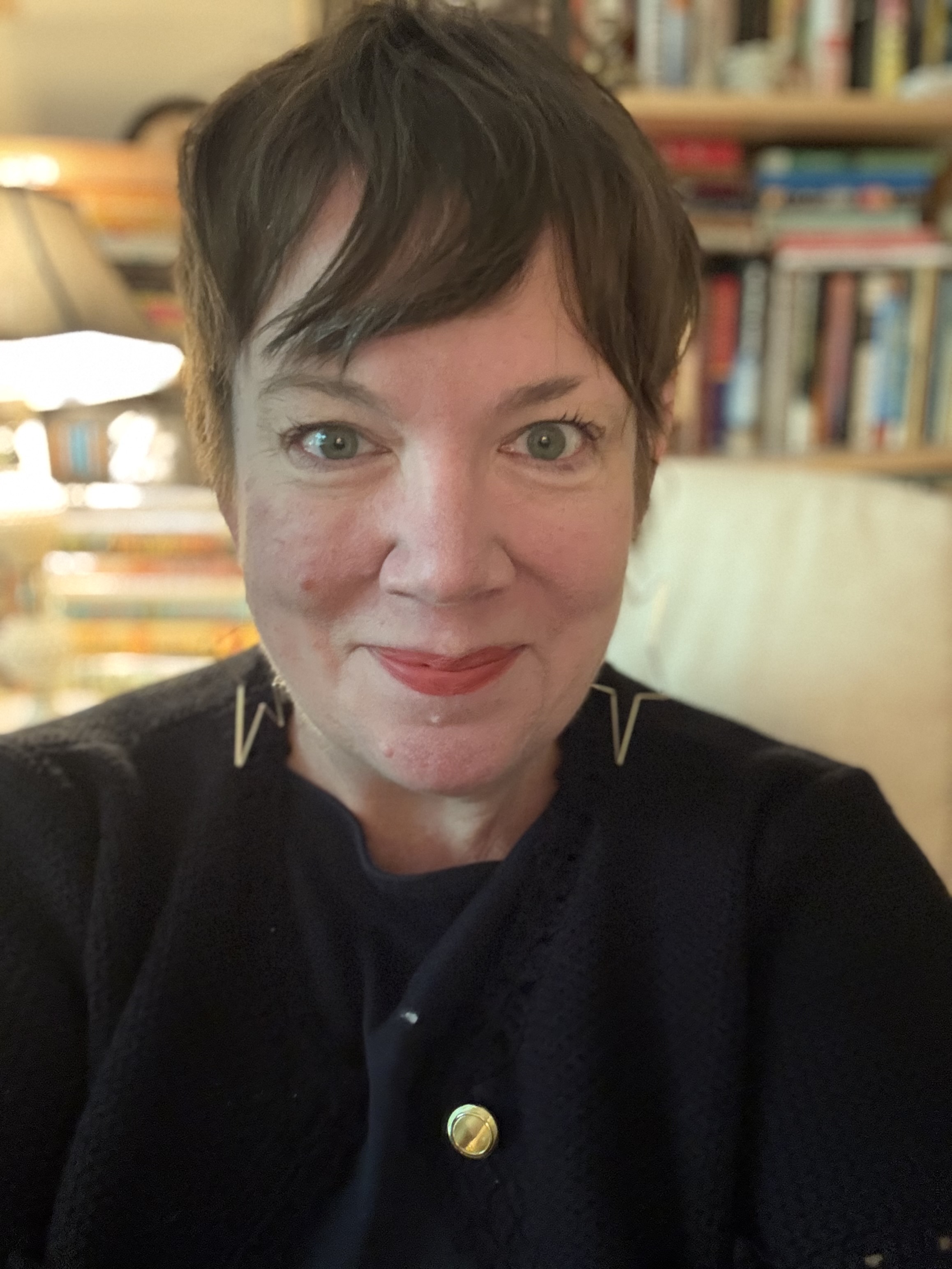 A woman with short brown hair and a black top smiles at the camera