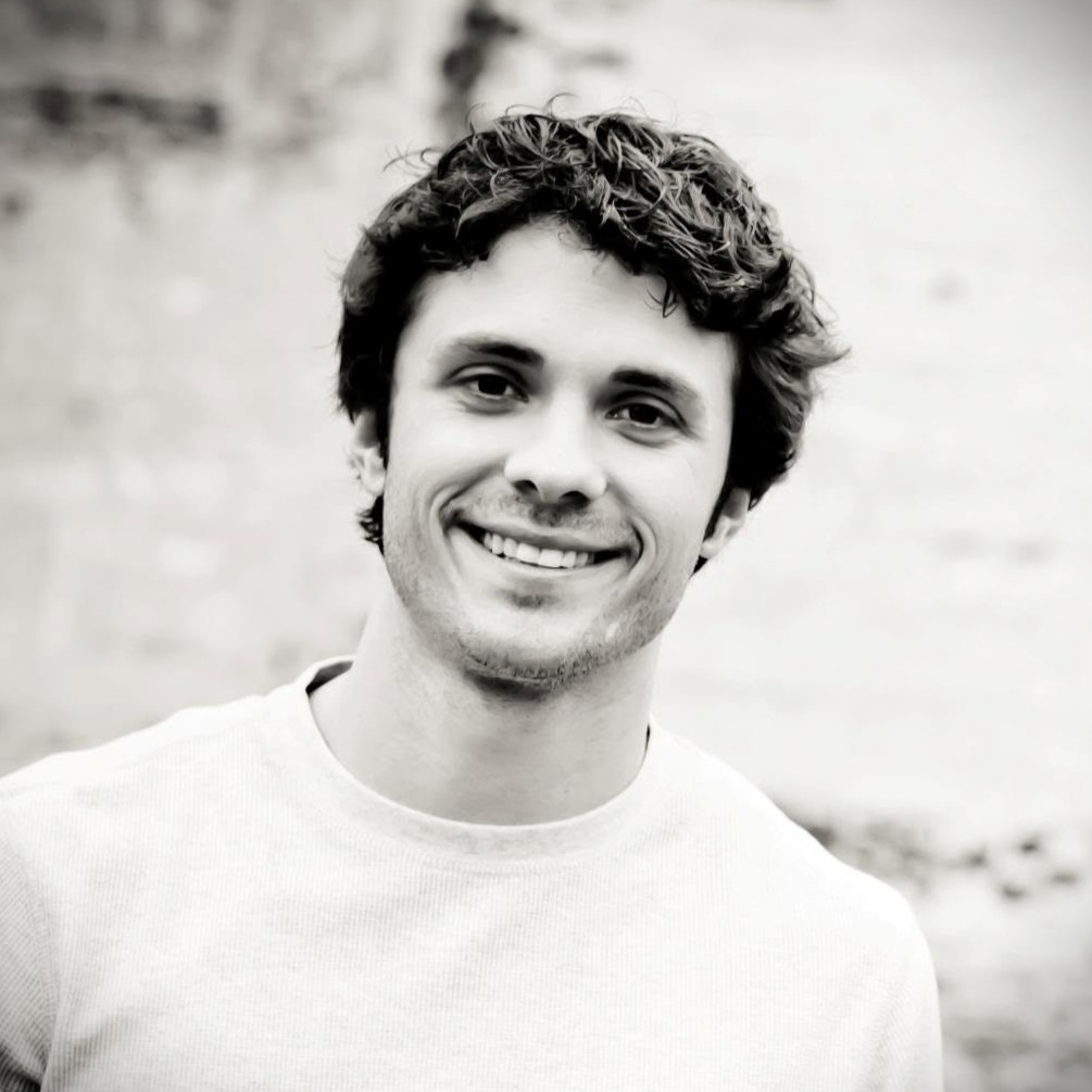 A black and white photo of a man with dark hair smiling at the camera