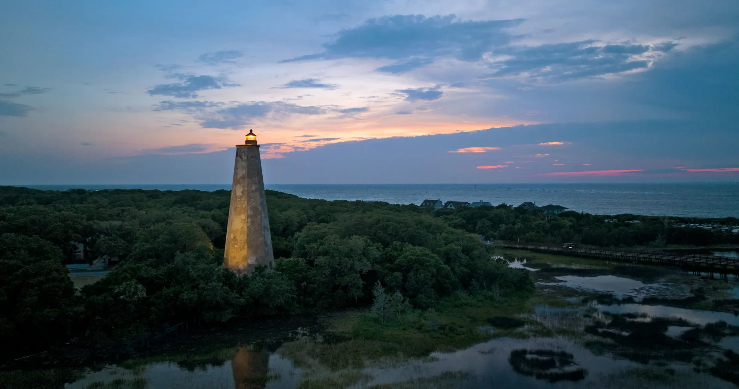 Aerial photo of Old Baldy Lighthouse on Bald Head Island at sunset.