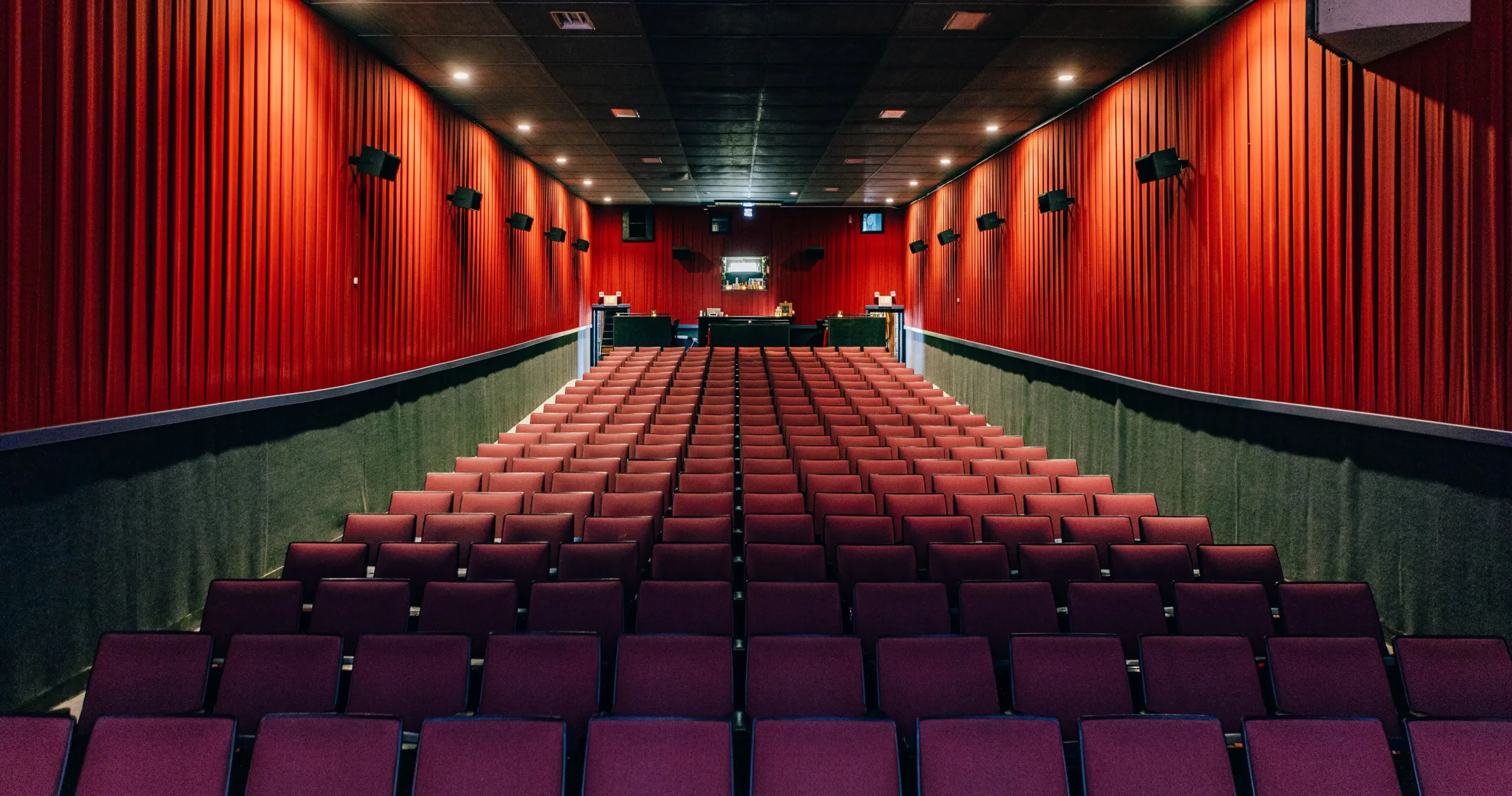 A moody interior image of the Pioneer Theatre seating with lush red walls 