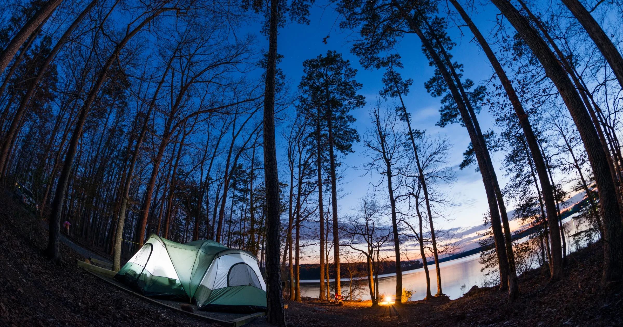 Moody wide-angle shot of tent on the edge of Badin Lake at dusk in Uwharrie National Forest.