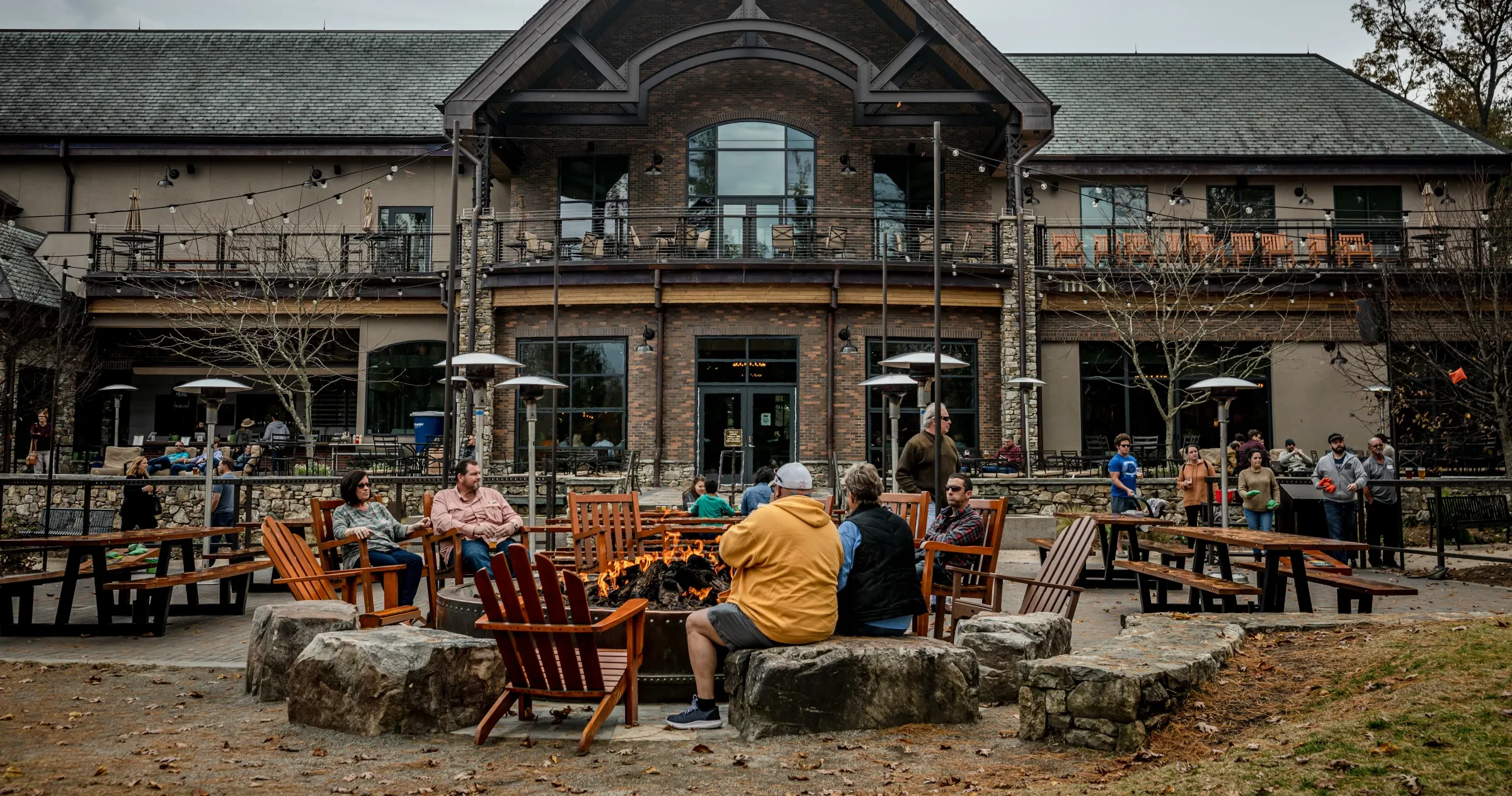 People sitting around fire outside at Sierra Nevada Brewing in fall.