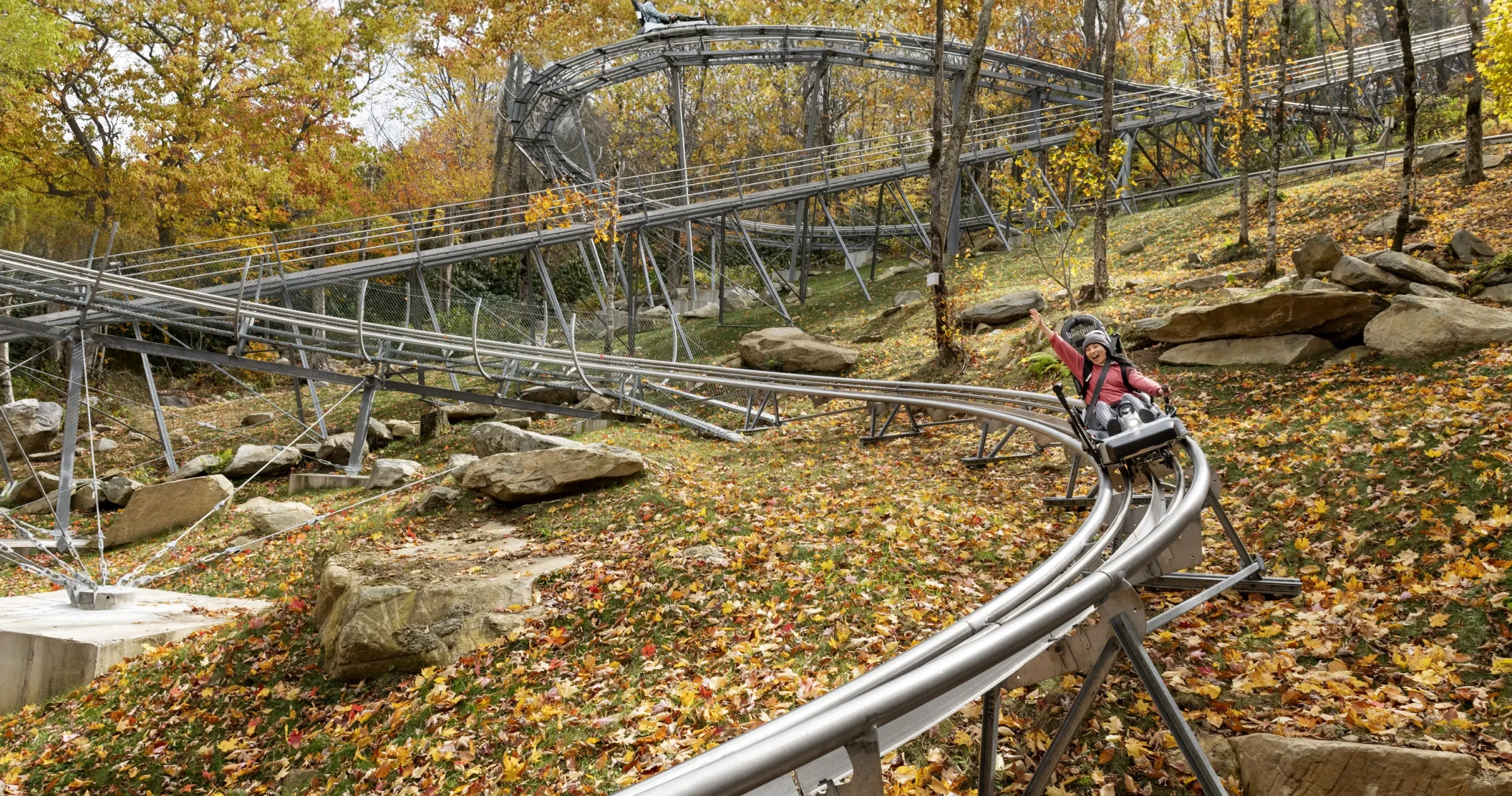 Woman smiling as she rides through the fall foliage at Wilderness Run Alpine Coaster outside of Banner Elk.