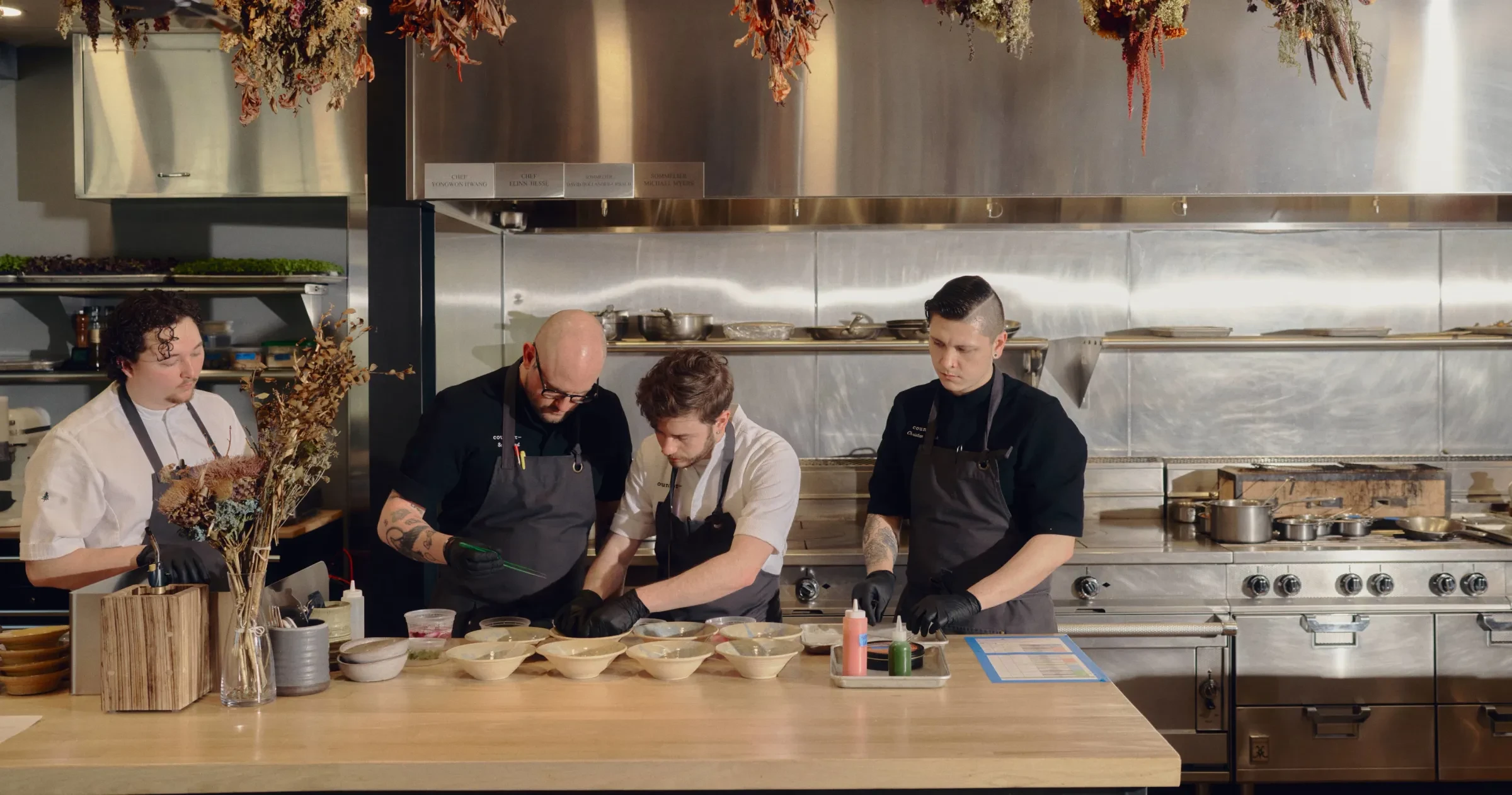 Four chefs plating dishes in kitchen at Counter, a One MICHELIN Star restaurant in Charlotte.