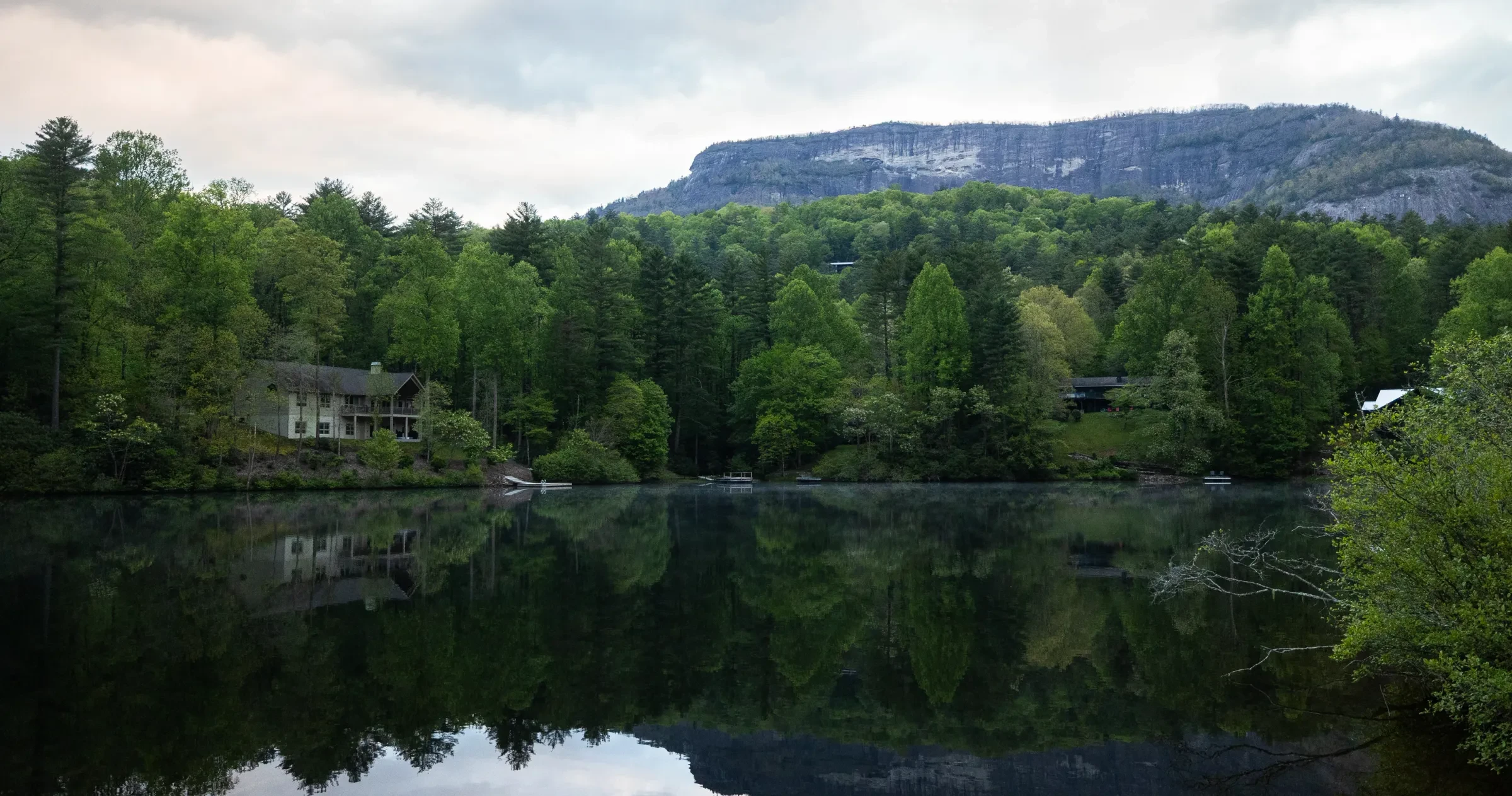 Calm Holly Berry Mountain Lake with woods surrounded water and mountains in distance.