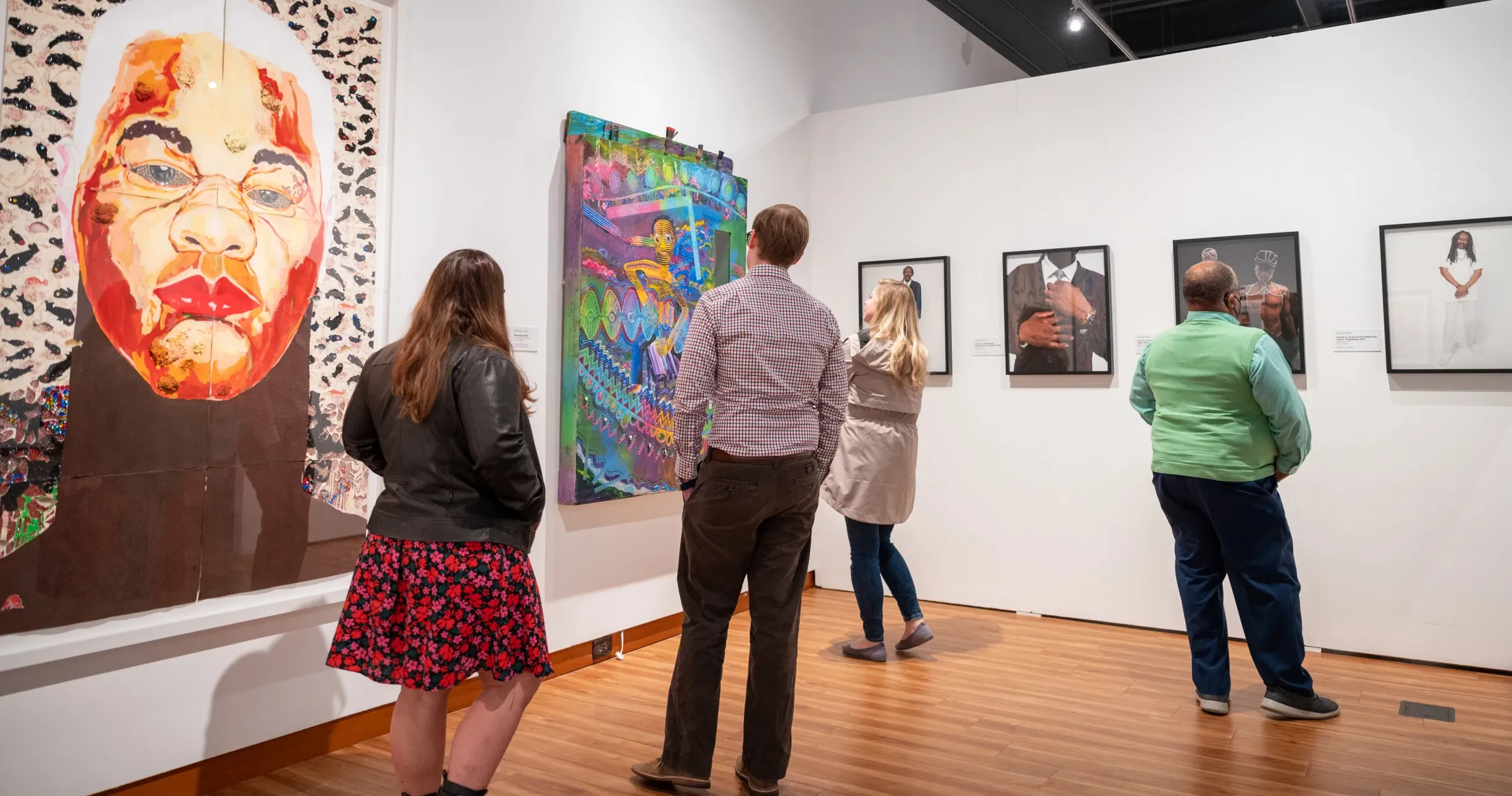 People inside museum admiring art on walls at Harvey B. Gantt Center.