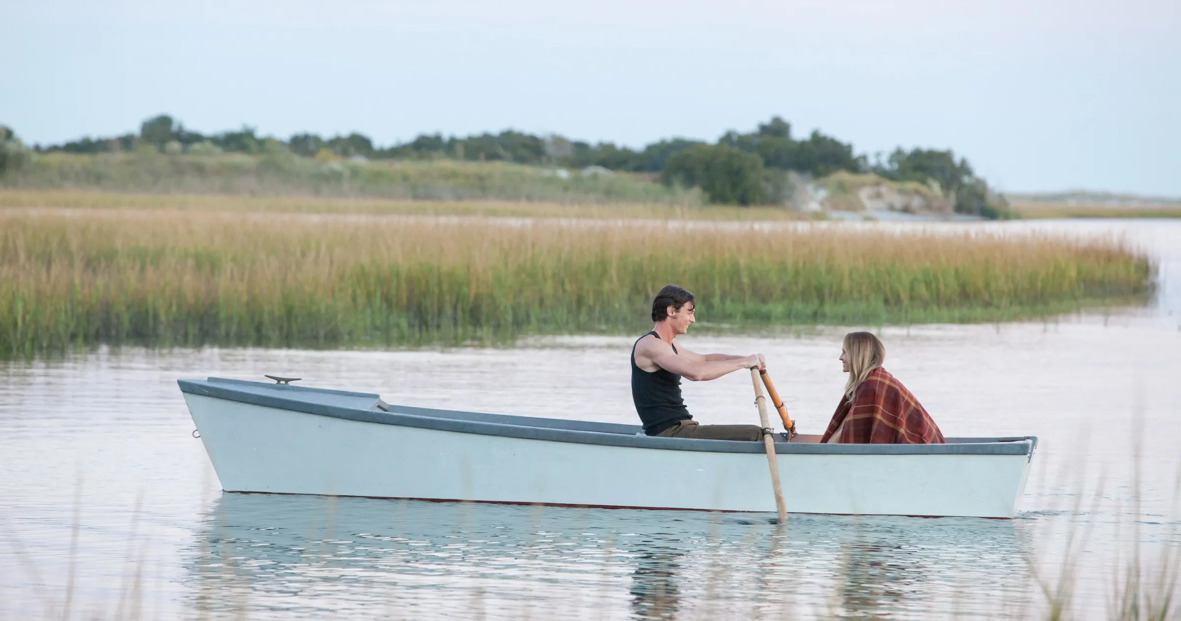 Couple from the film "The Choice" in canoe on calm marshy creek.