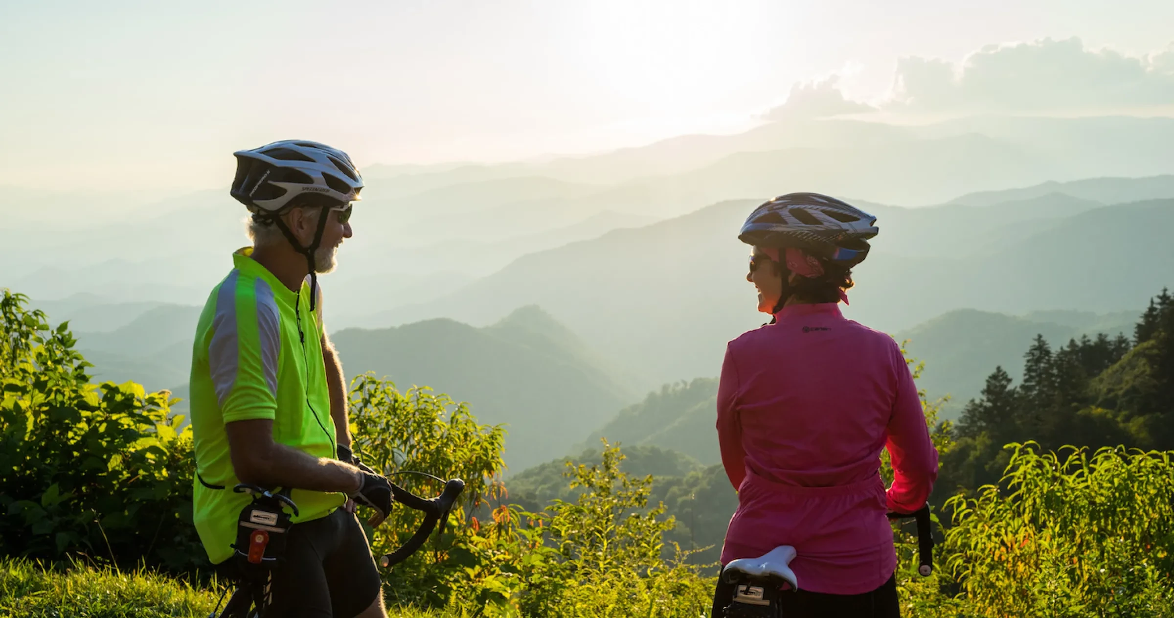 Two people on bikes taking a break on Blue Ridge Parkway to admire view.