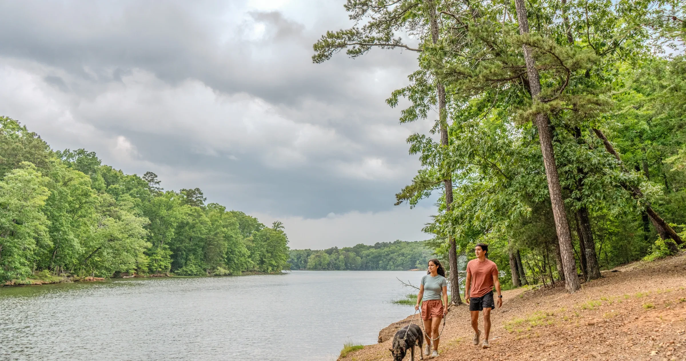 Couple walking dog along Badin Lake scenic path in Uwharrie National Forest.