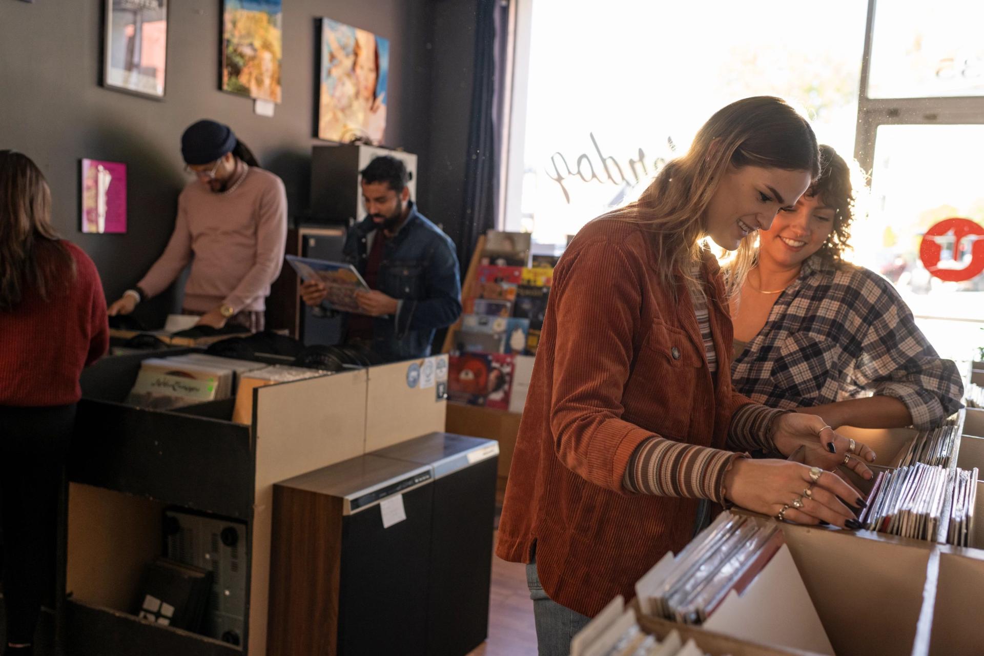 Two young women peruse records backlit by soft light at Underdog Records in Winston-Salem.