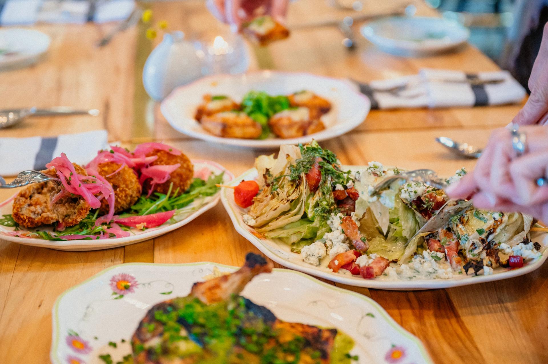 Beautiful plates of bright foods on ornate plates on table at Supperland.
