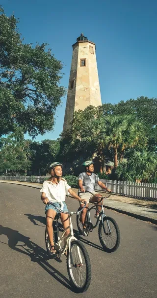 Young couple riding bikes away from the lighthouse on Bald Head Island.