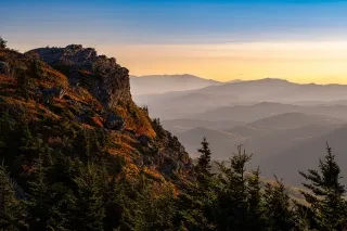 View of the side of Linville Peak with a colorful, hazy view of adjacent peaks. 