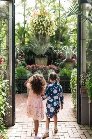 Two little girls walking through atrium of plants at Biltmore Estate.