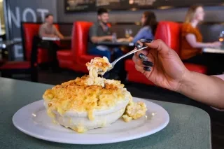 Mac Au Gratin from Poole's Diner with diners in booth in background.