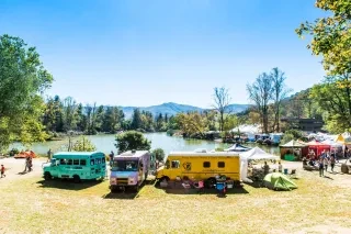 Colorful Trucks and crowds of people gather around a lake 