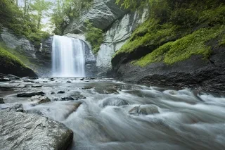 Landscape shot of Looking Glass Falls in Brevard during daytime. Greenery and rushing water visible.