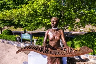 Bronze Nina Simone statue with green trees in background during daytime.