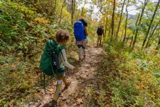 Family of three hiking through fall foliage on Appalachian Trail.
