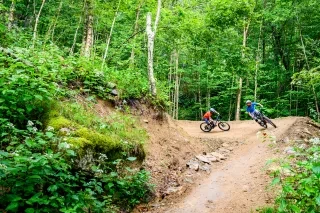 Friends mountain biking down trails in Beech Mountain in summer.