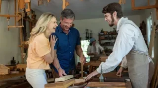 Couple talking and laughing with woodworker in studio at Old Salem.