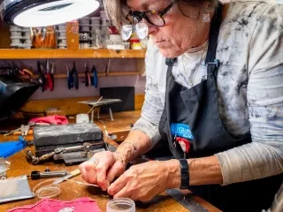 Woman working on hand-made craft at work station.