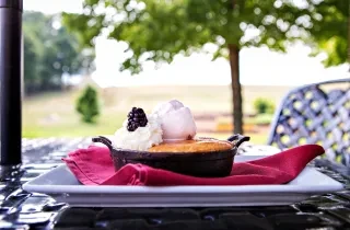 Closeup of sonker dessert on plate with vineyard grounds in background.