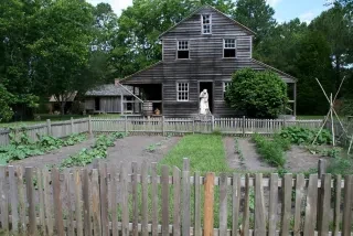 Woman sweeping steps of old house at Island Farm on NC's Outer Banks.