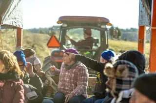 Group of people on hayride at U-pick Christmas tree farm during daytime.