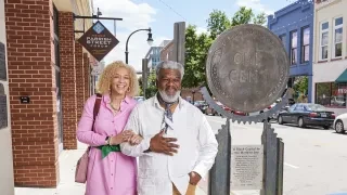 Couple walking down Durham street surrounded by Black History markers and signage.