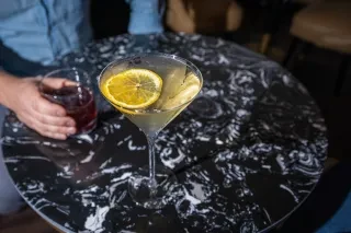 Two beautiful cocktails sitting on black and white marble table at cocktail bar.