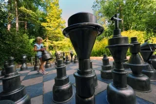 Girl moving large chess piece on human-sized chess board in Chapel Hill park.