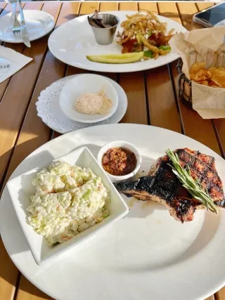 Plates of food and sides on table at dinnertime.