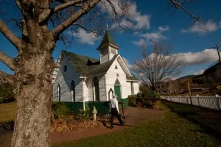 Man Walking into St. Mary's Church, home to a Ben Long fresco, in fall.