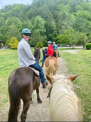 Three family members on horses looking back and smiling at camera.