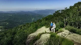 Couple and dog hiking on Emerald Outback with long-range mountains view in distance.