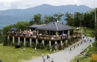 Aerial of 5506' Skybar with tons of people around grounds and on porch with mountains in distance.