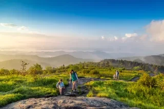 Family hiking up Black Balsam Knob with beautiful mountains in distance.