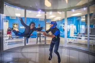 Young boy skydiving in wind tunnel with instructor. 
