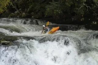 Person kayaking down Nantahala River rapids in summer.
