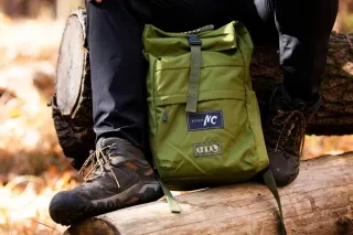 A close-up view of an Outdoor NC–branded backpack and worn hiking boots captures a moment of rest on a log during a fall outing at Forest Ridge State Park in Wake Forest, NC.