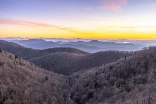 Mountain vistas on snowy winter day as sun rises in distance.