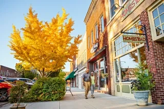 Couple holding hands walking down sidewalk on Main Street in downtown Hendersonville in fall.