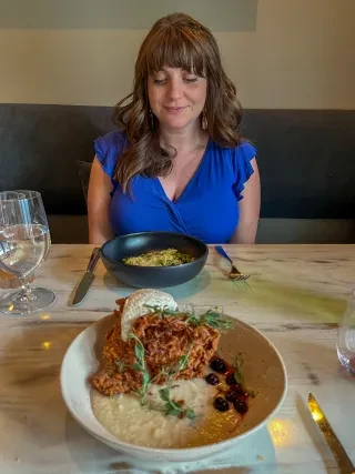 Woman in blue dress sitting at restaurant table looking at meal at Reid's Cafe.