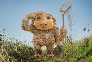 The troll Taks created by artist Thomas Dambo stands in an open field