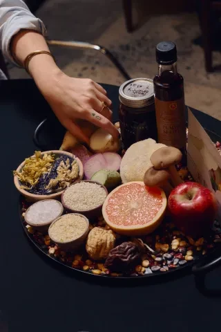Hand reaching for a potato from a tray of fresh fruits and vegetables