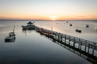 Calm sound and gazebo extended into water as sun sets in distance during winter day in Corolla.