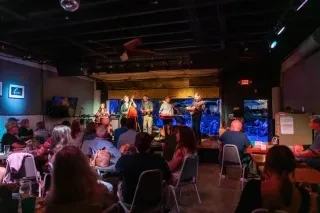 Band performing on stage at 185 King Street with patrons sitting at tables watching.